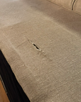 Condition photo: the 3 inch tear in the linen on the outside back panel, a clean slit with the weave intact around it