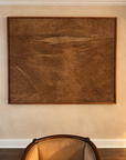 Untitled (Rust) by Nicole Daedone, framed handmade paper in rust and umber tones hung above an armchair