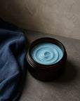 Indigo whipped body butter in an amber jar with indigo linen