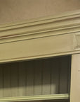 Close-up of the stepped cornice, square corner block and beadboard back in glazed olive green paint