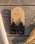 Gye W'Ani Adinkra earrings in black by The Ariana Collective, on a kraft tag