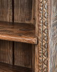 Shelf edge and carved upright showing aged wood and finish wear.