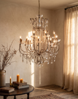 Antique crystal beaded chandelier lit and hanging over a round table in a warm plaster room