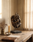 Senufo sacrifice mask styled in a warm lived-in interior with a candle and antique book