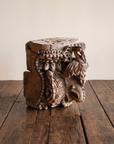 Carved teak temple capital, three-quarter view, on a reclaimed wood floor