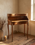 Vintage burl walnut writing desk beside a tall window, soft light