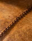 Close-up of the burnished cognac leather and hand-braided whipstitch seam