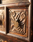 Macro detail of the hand-carved bird and blossom drawer panel with brass ring pull