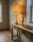 Antique brass table lamp in warm window light on a console