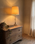 Antique brass table lamp three-quarter view on a weathered chest