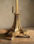 Macro detail of the fluted brass base, acanthus feet and tasseled pull-chain