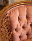 Macro detail of button-tufted rose velvet meeting the woven cane side panel