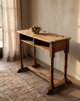 Three-quarter view of the antique school desk showing turned legs and trestle base