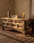 Antique Chinese carved elm altar coffee table styled with a stoneware vessel, books and a candle in a warm room
