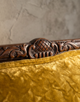 Macro detail of the hand-carved crest medallion and crushed gold velvet texture