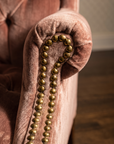 Macro detail of the rolled arm and double-row antique brass nailhead trim