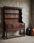 Antique oak Welsh dresser in a greige plaster room, without linen drape, styled with stoneware vessels and dried branches