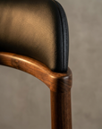 Macro detail of the black leather stitching and walnut top rail joint