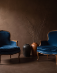 Both Blue Velvet Bergere chairs together in the brown plaster room