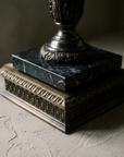 Macro detail of the black veined marble slab on the square bronze plinth with gadrooned moulding