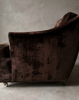 Side profile of the chocolate velvet club chair showing the concave sweep of the outside back from top rail down to the base