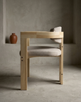 Side profile of the sueded white armchair showing the flat arm rail running back to the curved back rail and the paired rear stiles