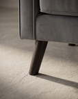 Macro detail of the tapered espresso wood leg meeting the square track arm