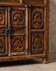 Macro detail of the cabinet doors, forged iron hasp, and carved medallion panels