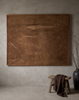 Bare Umber fabric panel hung on a greige plaster wall, styled with stoneware vessels and dried branches