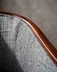 Macro detail of the grey-blue bouclé weave and mahogany trim at the seat corner