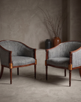Vintage mahogany barrel-back chairs, grey-blue bouclé, pair, against raw plaster wall