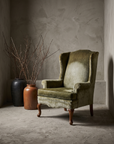 Single green velvet wingback chair, 45 degree three-quarter view