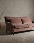 Taylor King dusty rose velvet English roll-arm sofa, lifestyle hero shot in a greige plaster room