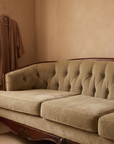 Light sage velvet tufted sofa, close warm view with a silk robe hanging nearby