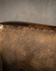 Macro detail of the nailhead trim along the arm top and the leather patina