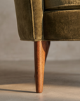 Macro detail of tapered walnut leg meeting the upholstered waterfall base