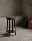 Alternate angle of the rustic accent stool in a plaster room with stoneware vessels and dried branches
