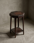 Three-quarter view of the rustic accent stool showing the octagonal top, tapered legs, and lower shelf