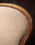 Detail of brass nailhead trim tracing the linen and leather seam on the chair back