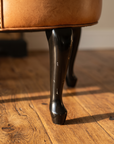 Detail of the glossy black cabriole front leg and pad foot
