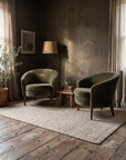 Vintage Dialogica moss green chenille velvet barrel chairs in an atmospheric Axel Vervoordt style living room with rough plaster walls and reclaimed wood floors