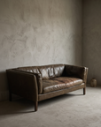 Cognac leather track-arm sofa, worn and lived-in patina, 45 degree three-quarter view showing form and construction