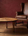 Antique round coffee table, lighter, as a side table beside the leather wingback chair