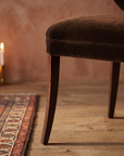 Detail of the tapered saber leg and seat cushion edge stitching, warm domestic room