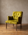 Chartreuse velvet diamond-tufted vintage armchair, three-quarter lifestyle view in a plaster and reclaimed-wood room