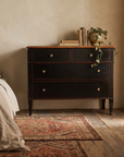 Atelier de Madeleine chest in a warm bedroom setting beside a linen-dressed bed, kilim rug, Axel Vervoordt wabi-sabi style