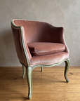 Front angle of the rose velvet bergère with cabriole legs on a reclaimed wood floor