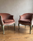 Pair of vintage Louis XV style bergères en gondole in dusty rose velvet with painted sage green frames, side by side against a plaster wall on a reclaimed wood floor