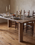 Redwood dining table in daylight with stoneware plates, clear artisan water glasses, brass candlesticks and a bowl of fruit