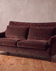 Taylor King espresso brown velvet English roll-arm sofa, hero shot against a tadelakt plaster wall and reclaimed wood floor